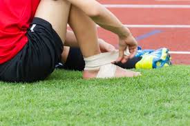 Sports ankle injury — athlete with strapped ankle on a running track